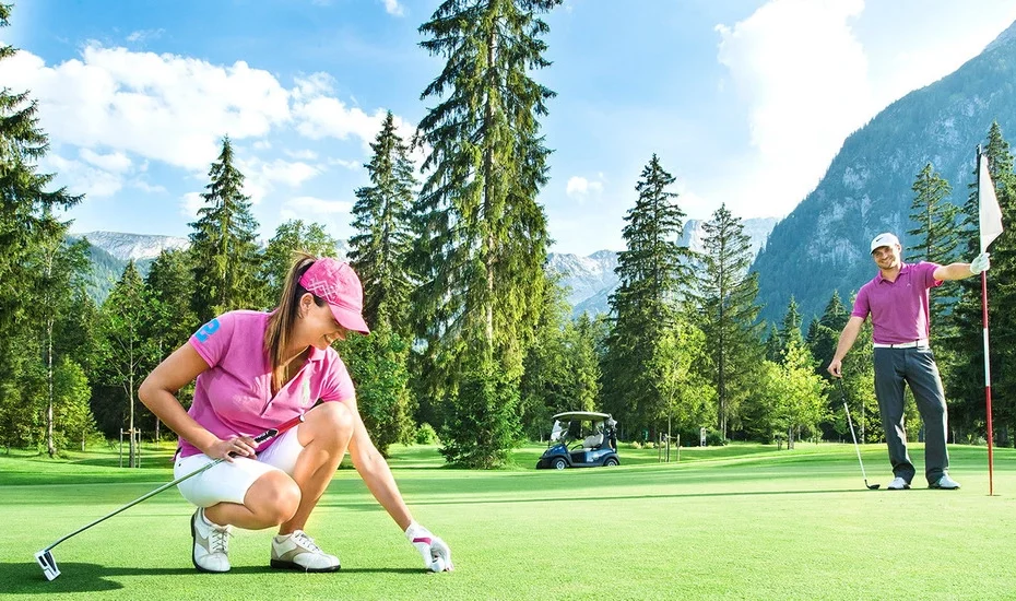 Ein Paar spielt Golf auf dem Golfplatz ihres Golfhotels in Österreich