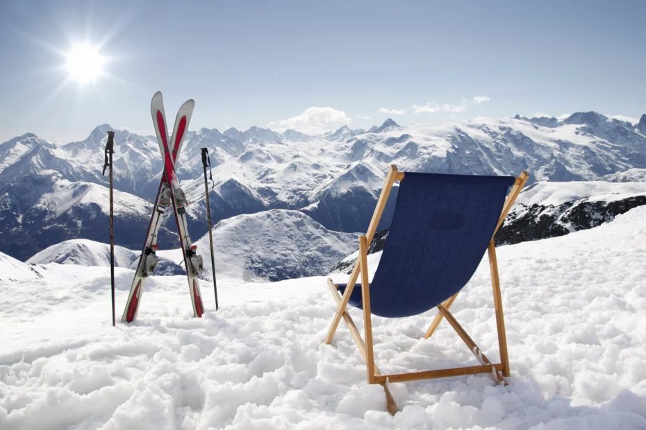 Liegestuhl und Skier im Skiurlaub auf einer sonnigen Piste